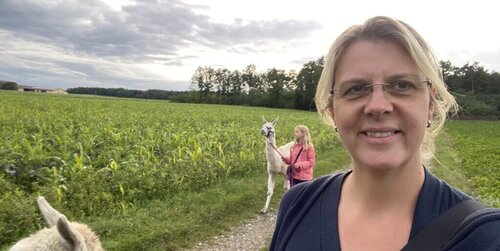 Ulrike macht einen Selfie mit Tochter und Alpakas im Hintergrund